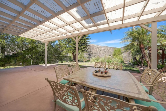 view of patio with outdoor dining space, a mountain view, and a pergola