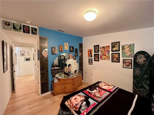 bedroom featuring a textured ceiling, visible vents, and light wood-style floors