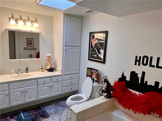 bathroom featuring toilet, a skylight, vanity, and visible vents