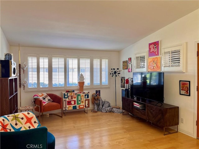 living room with vaulted ceiling, light wood finished floors, a wealth of natural light, and baseboards