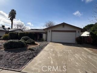 ranch-style home with an attached garage, fence, and concrete driveway