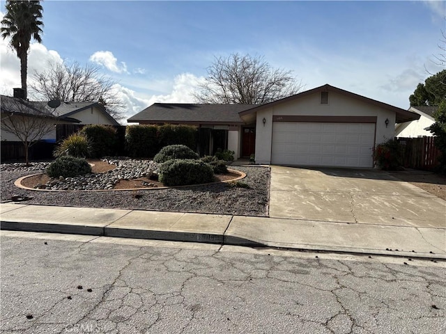 view of front of house featuring a garage, concrete driveway, fence, and stucco siding