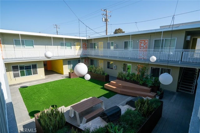 view of property's community featuring a lawn and a patio