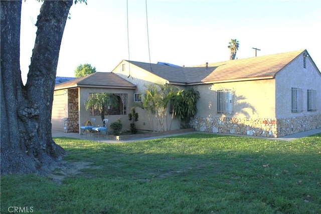 single story home featuring stone siding, a patio area, stucco siding, and a front yard