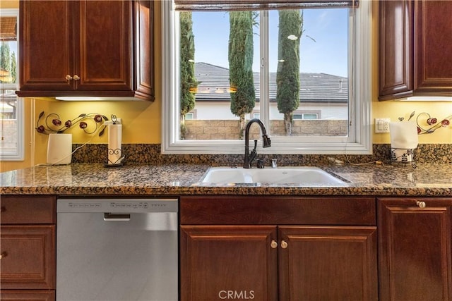 kitchen with a sink, dark stone counters, and dishwasher