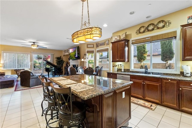 kitchen featuring light tile patterned floors, a breakfast bar, open floor plan, a fireplace, and a sink