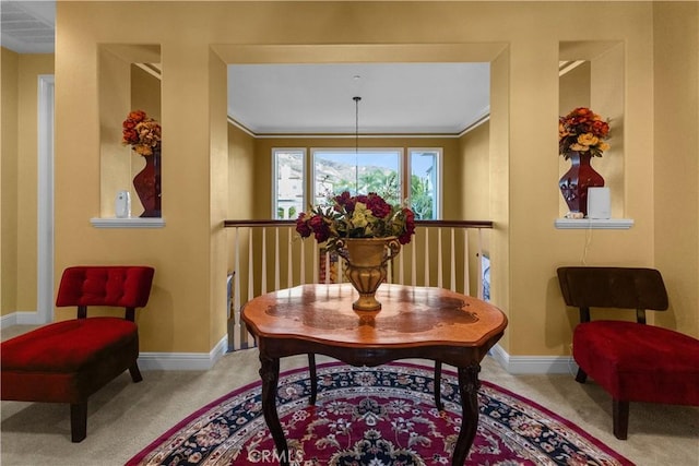 sitting room with carpet, crown molding, baseboards, and an inviting chandelier