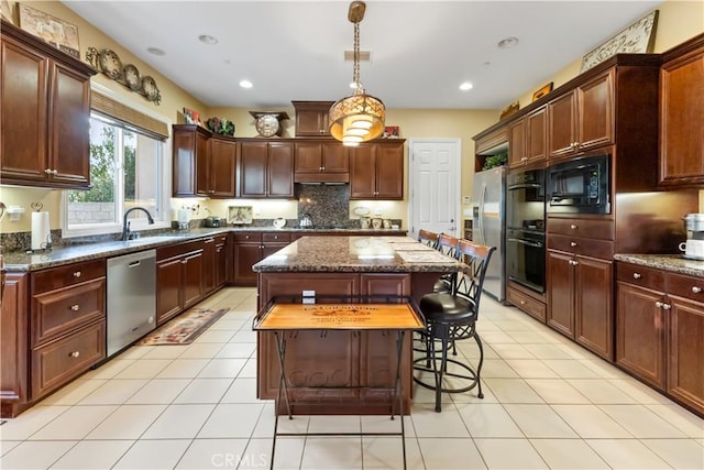 kitchen featuring light tile patterned floors, visible vents, dark stone counters, a center island, and black appliances