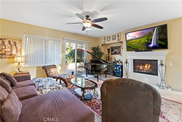 living room featuring ceiling fan and a glass covered fireplace
