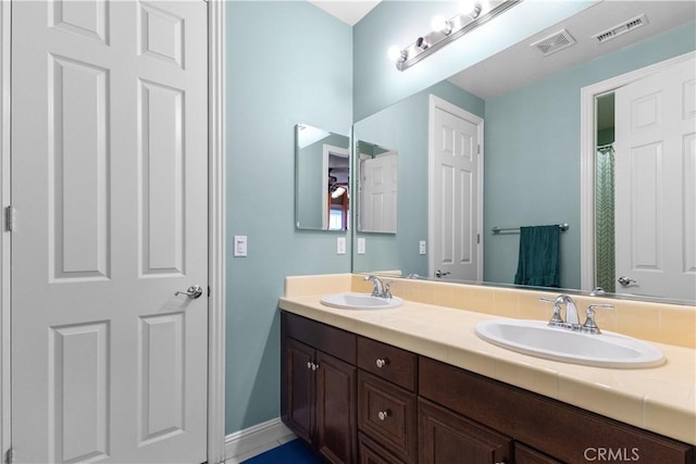 bathroom with double vanity, visible vents, and a sink