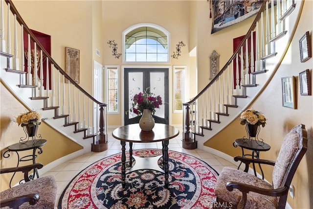 tiled entrance foyer featuring a high ceiling, visible vents, and baseboards