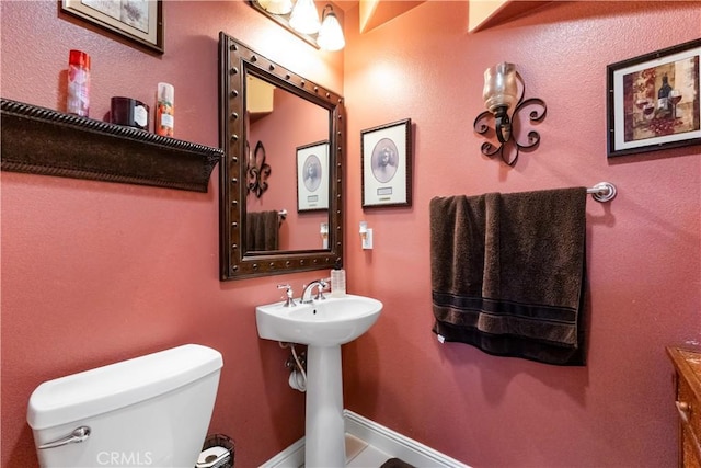 bathroom with toilet and baseboards