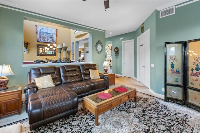 living area featuring baseboards, visible vents, a ceiling fan, and ornamental molding