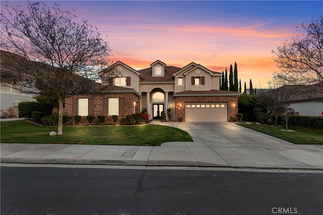 traditional-style house with a garage, concrete driveway, brick siding, and a lawn