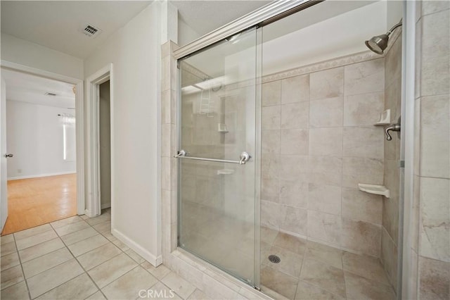 full bath with a stall shower, tile patterned flooring, visible vents, and baseboards