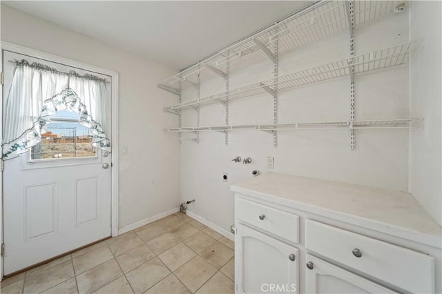 clothes washing area with washer hookup, cabinet space, hookup for an electric dryer, light tile patterned flooring, and baseboards