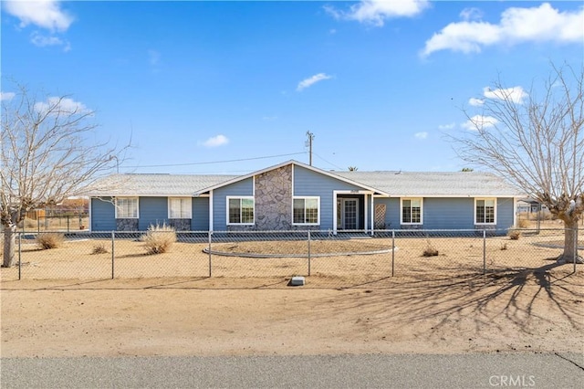 ranch-style home featuring stone siding and a fenced front yard