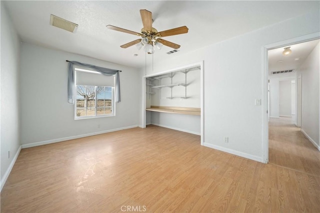 empty room featuring light wood-type flooring, visible vents, and a ceiling fan