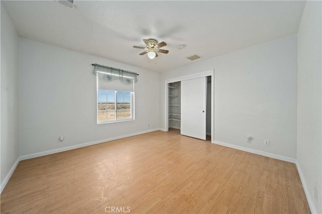 unfurnished bedroom with baseboards, visible vents, a ceiling fan, light wood-style floors, and a closet