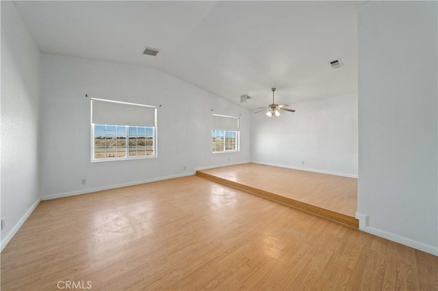 spare room featuring a ceiling fan, visible vents, vaulted ceiling, and light wood-style flooring