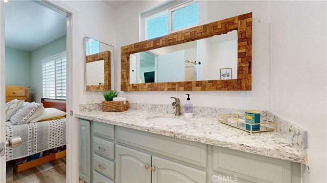 ensuite bathroom with vanity, ensuite bath, and wood finished floors