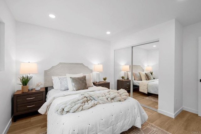 bedroom with light wood finished floors, baseboards, a closet, and recessed lighting