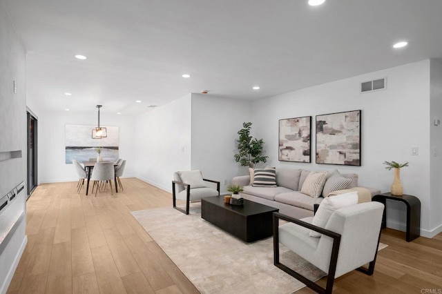 living room featuring baseboards, light wood-type flooring, visible vents, and recessed lighting