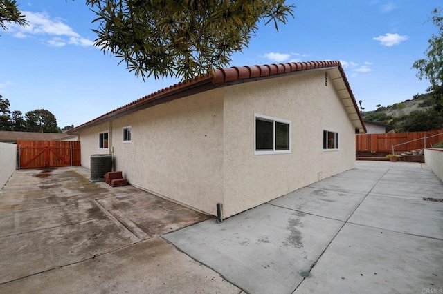 rear view of house with a patio area, fence, cooling unit, and stucco siding