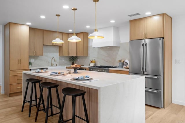 kitchen with premium range hood, stove, visible vents, light wood-style floors, and freestanding refrigerator