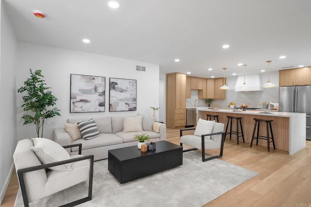 living room featuring light wood-style flooring, visible vents, and recessed lighting