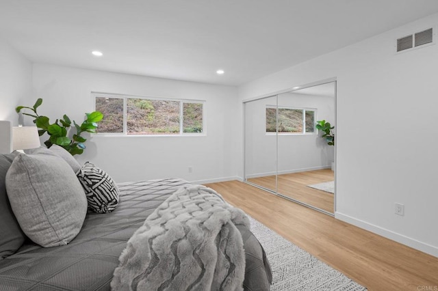 bedroom featuring baseboards, visible vents, multiple windows, and wood finished floors