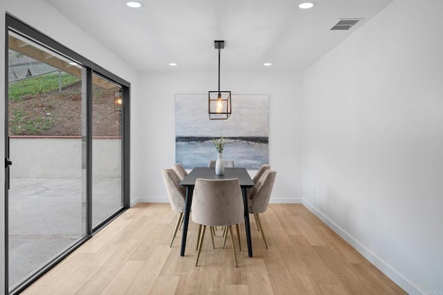 dining area with light wood-style floors, visible vents, and baseboards