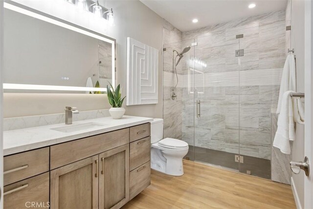 full bathroom with toilet, a shower stall, wood finished floors, and vanity