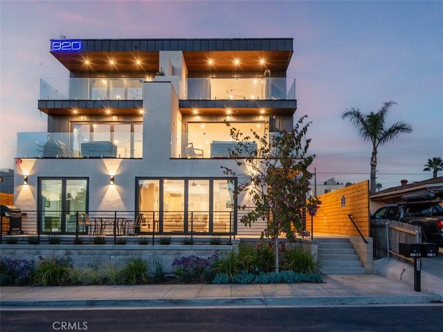 exterior space with fence, a balcony, and stucco siding