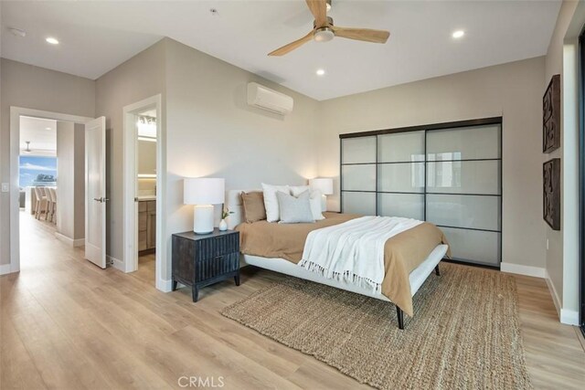 bedroom with a wall unit AC, recessed lighting, light wood-style floors, ceiling fan, and baseboards