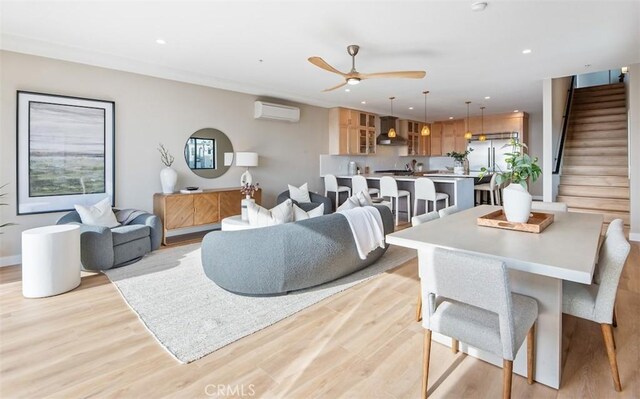 living area with recessed lighting, a wall unit AC, stairway, and light wood finished floors