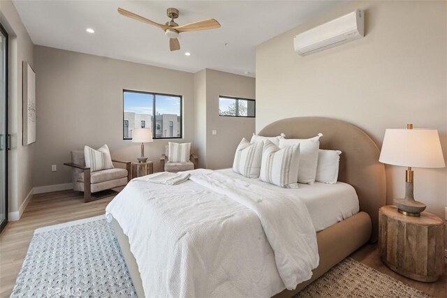 bedroom featuring recessed lighting, an AC wall unit, baseboards, and light wood finished floors