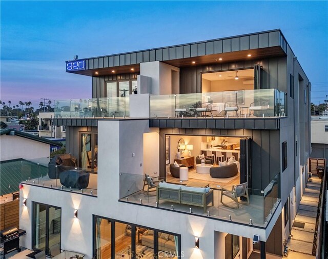 back of property at dusk featuring a balcony