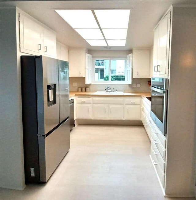 kitchen featuring light countertops, appliances with stainless steel finishes, a sink, and white cabinets