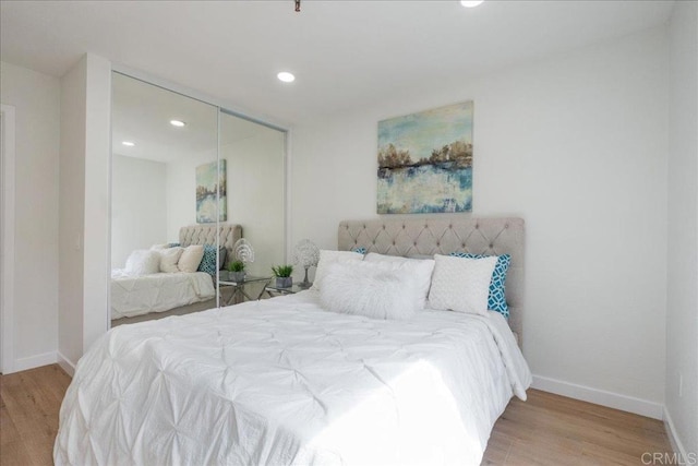 bedroom with a closet, baseboards, wood finished floors, and recessed lighting