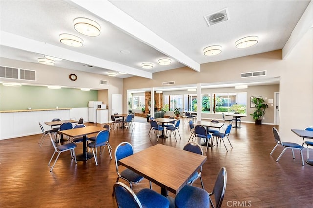 dining space with a healthy amount of sunlight, visible vents, and beamed ceiling