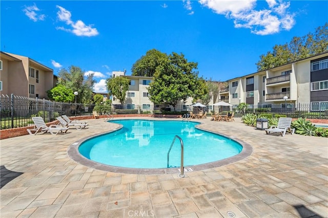 community pool with a residential view, fence, and a patio