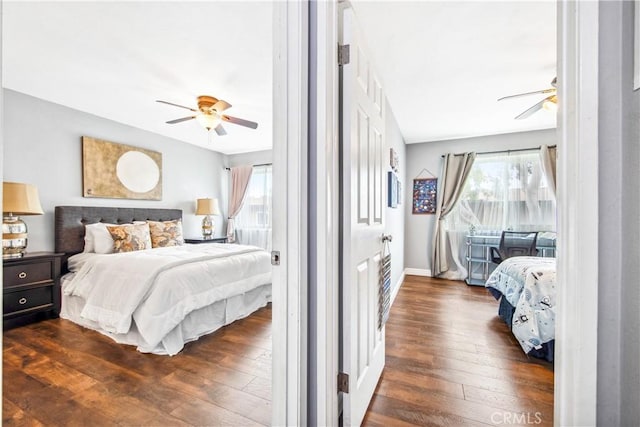 bedroom with ceiling fan, multiple windows, and dark wood-style flooring