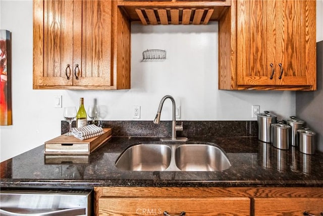 kitchen with dark stone counters, a sink, and brown cabinets