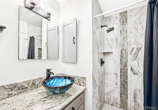 full bathroom featuring tiled shower and vanity