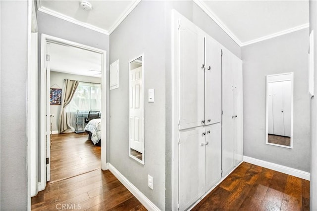 hallway with dark wood-style floors, crown molding, and baseboards