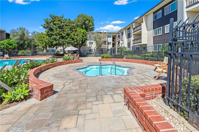 pool featuring a residential view, fence, a community hot tub, and a patio