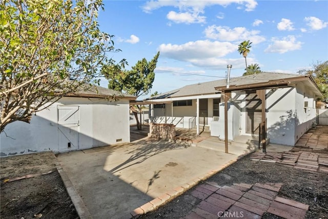 back of house featuring stucco siding, an outdoor structure, a patio, and fence