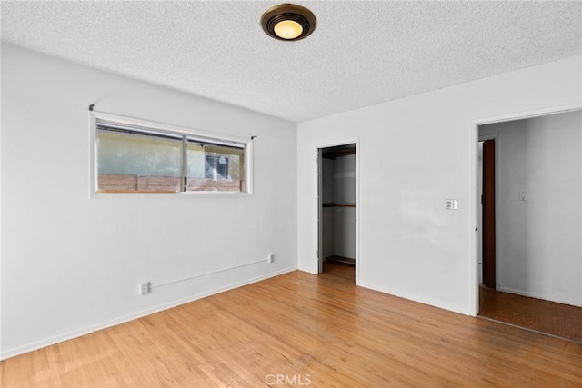 unfurnished bedroom with baseboards, light wood-type flooring, a closet, and a textured ceiling