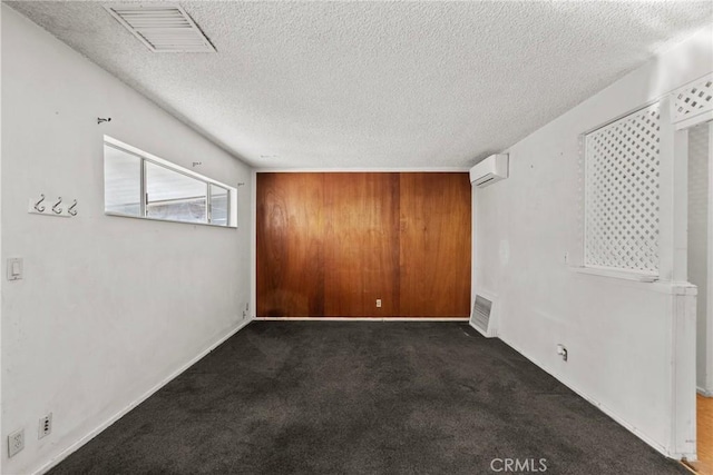 empty room featuring visible vents, a textured ceiling, a wall unit AC, and carpet floors